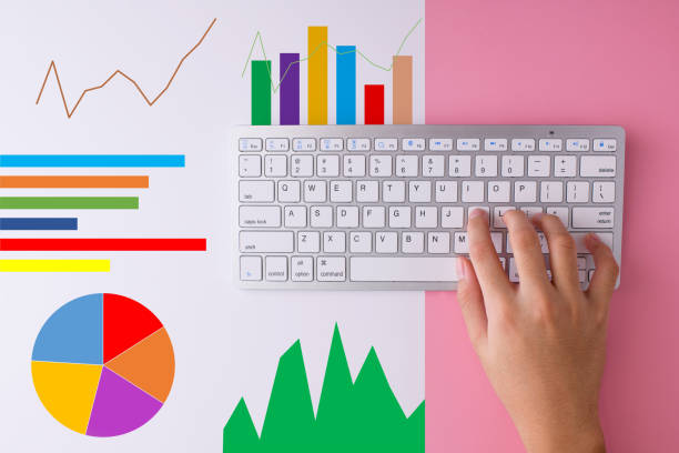 Hand typing on keyboard with charts as background