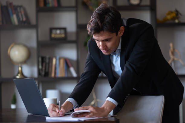 Handsome businessman in suit signing official document.